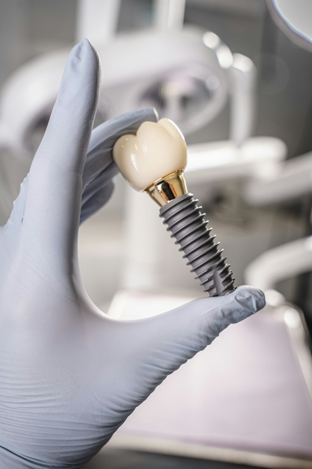 Implante dental y corona en una mano con guante